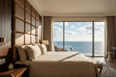 Svelte luxury grey linen bedsheet styled in an ocean-view bedroom with matching pillows and elegant self-jacquard botanical vine design.