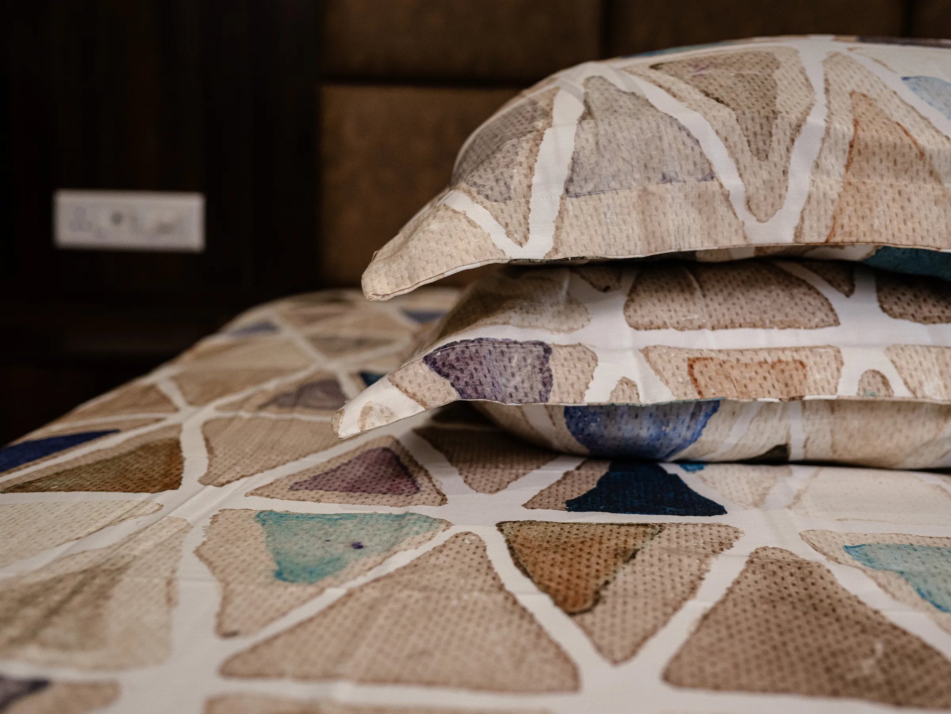 Detailed low-angle view of Vellum beige geometric bedsheet showing refined triangle artwork and breathable premium cotton fabric