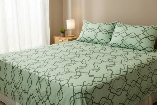 A lifestyle bedroom is set with a tea green geometric trellis bedsheet print crafted for a modern luxury bedroom aesthetic
