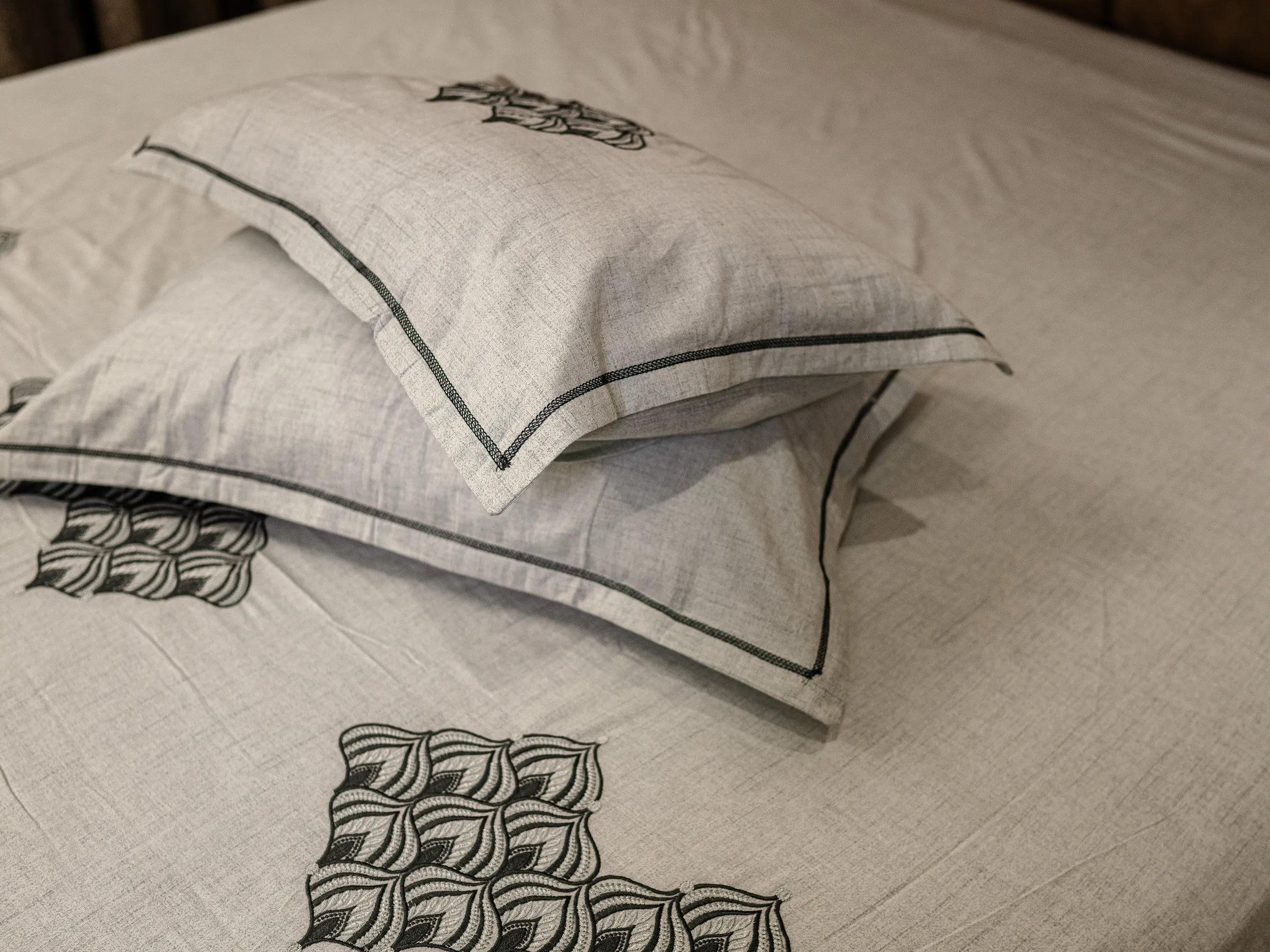 Solace luxury greyish blue cotton bedsheet with matching pillow covers, featuring hand-embroidered motifs and elegant piped edges for a refined bedroom look