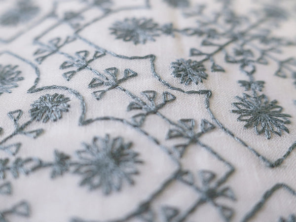 Close-up of embroidered ice blue pillow cover on 1000 thread count organic cotton bedsheet with elegant floral embroidery