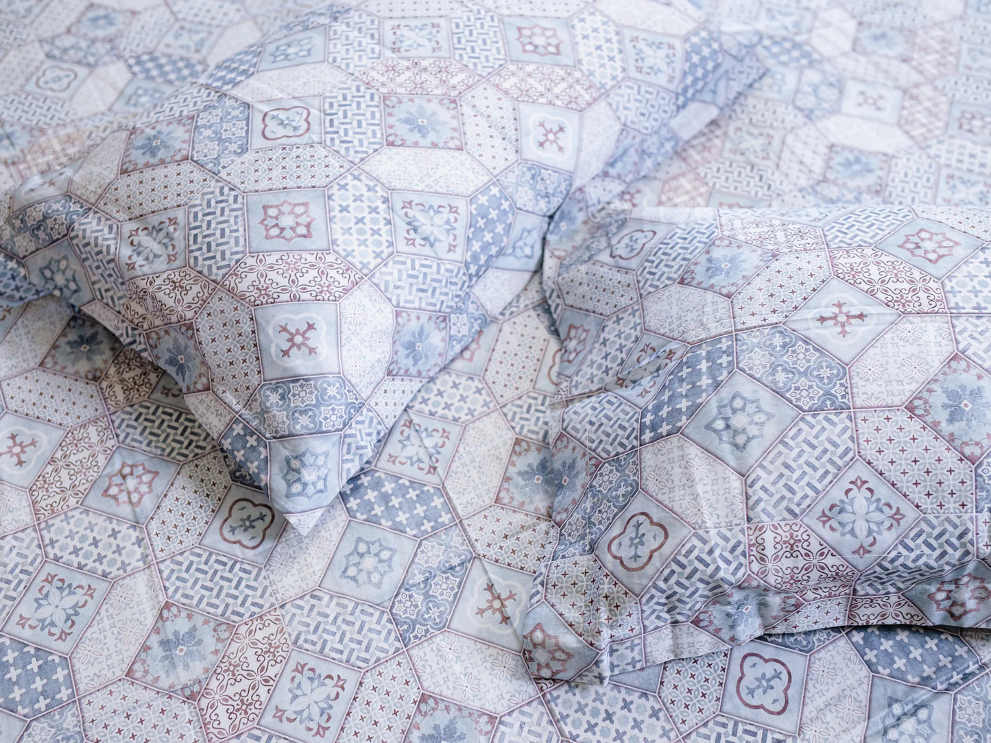 Two pillow cover corners kept side by side on Echelon 500 thread count indigo blue bedsheet with soft fabric folds and refined abstract print for a luxury bedroom look.