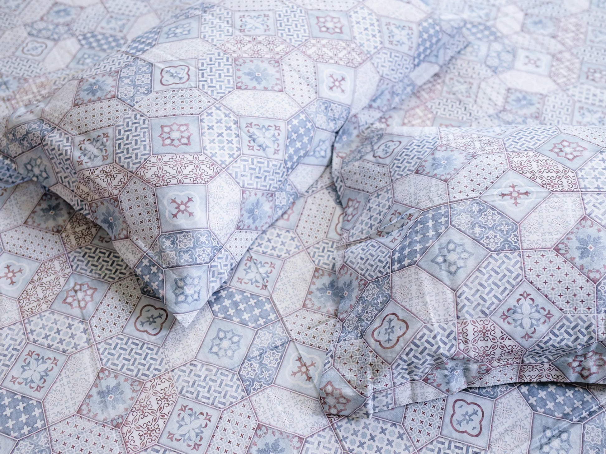 Two pillow cover corners kept side by side on Echelon 500 thread count indigo blue bedsheet with soft fabric folds and refined abstract print for a luxury bedroom look.