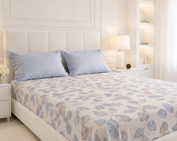 Tapestry luxury powder blue cotton bedsheet styled on a bright white bed with matching pillows and soft botanical leaf print