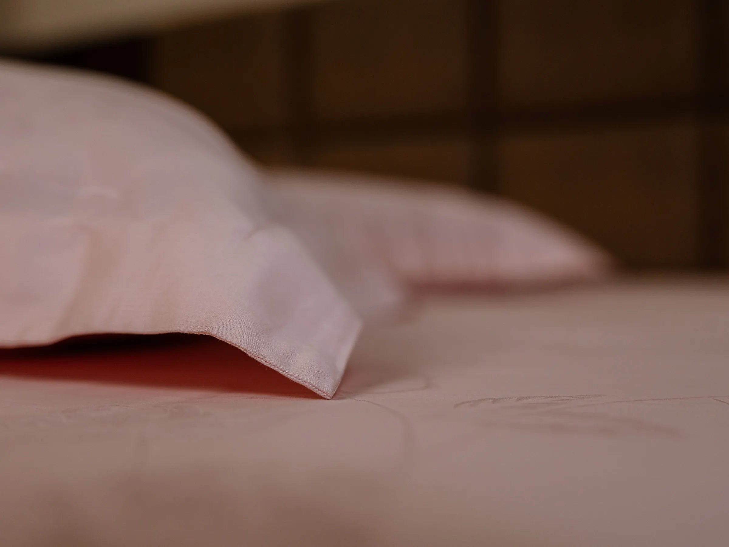 Close-up of a corner of pillow cover and bedsheet of color rose gold 1000 thread count organic cotton featuring elegant jacquard weave and soft breathable fabric