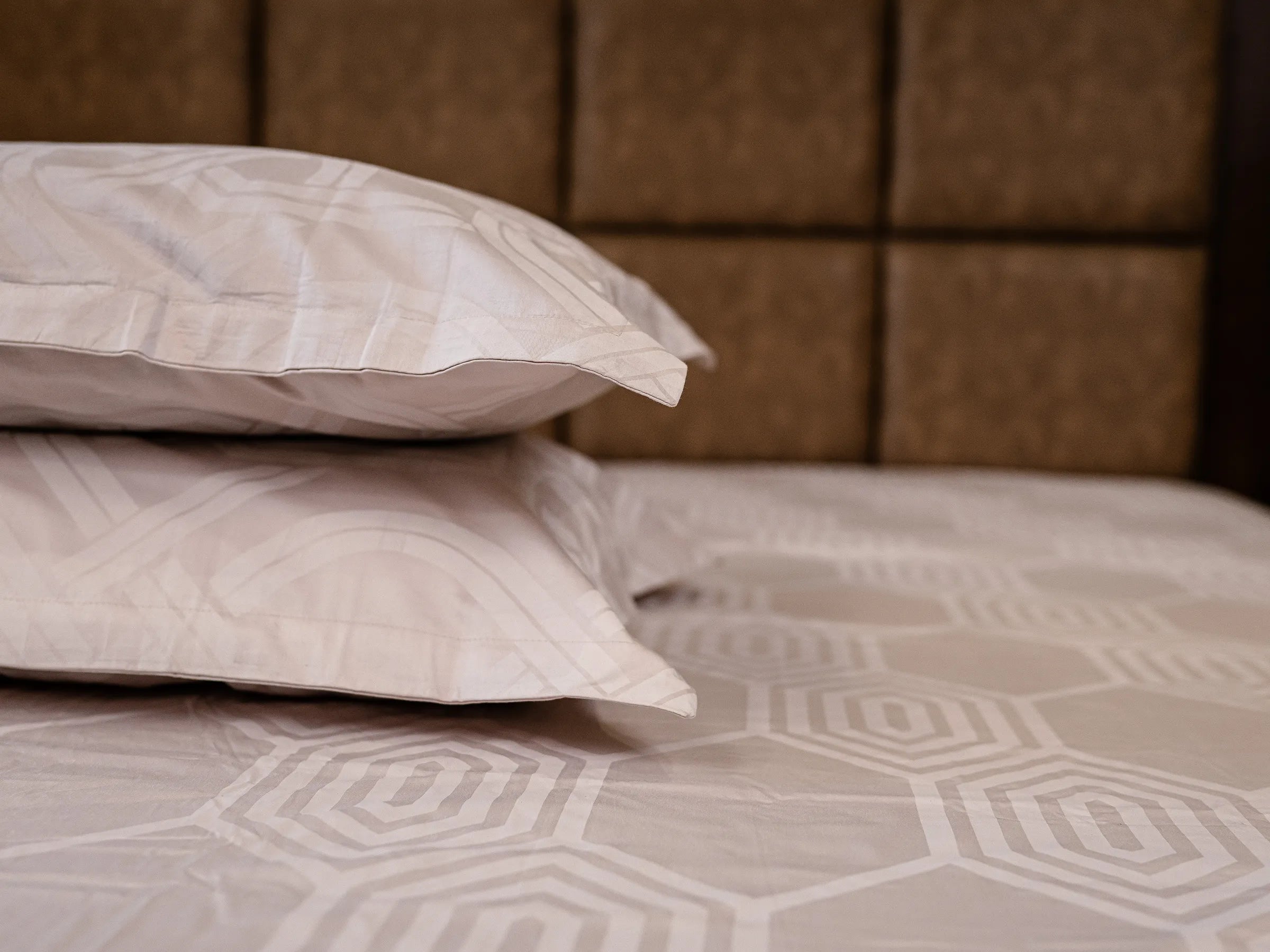 Aether luxury cotton bedsheet in steel grey styled with stacked pillows, highlighting breathable fabric and modern geometric pattern