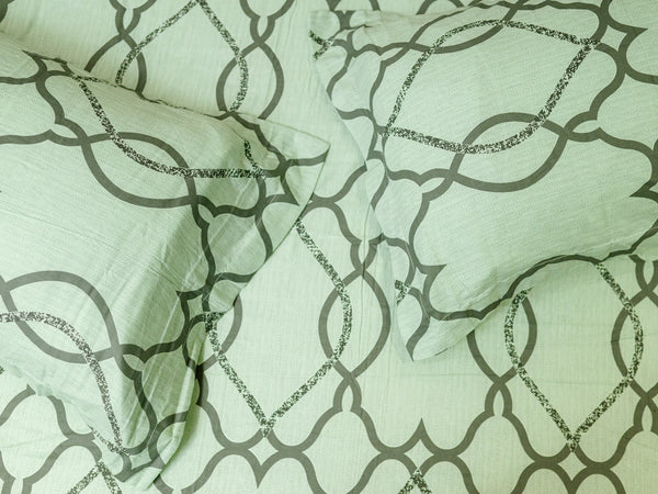 Close-up of Stasis tea green luxury bedsheet showcasing interlocking geometric trellis pattern on soft cotton fabric