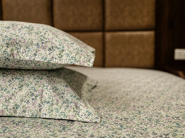 Two pillows kept one over another on a matching premium antique white floral organic cotton pillow covers with matching 500 thread count bedsheet on a super king bed