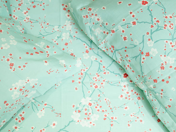 Close-up of Echo aqua luxury cotton bedsheet showcasing the delicate cherry blossom print and smooth 500 thread count fabric