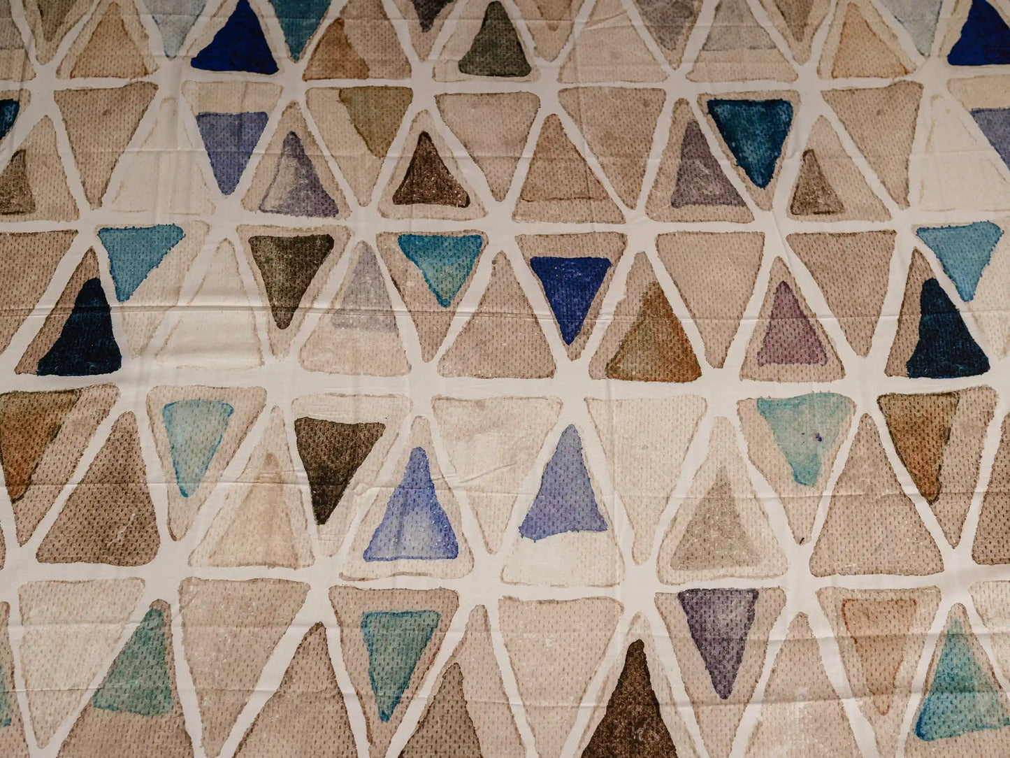Close-up of Vellum luxury cotton bedsheet showcasing beige triangle mosaic print with blue and neutral watercolor accents