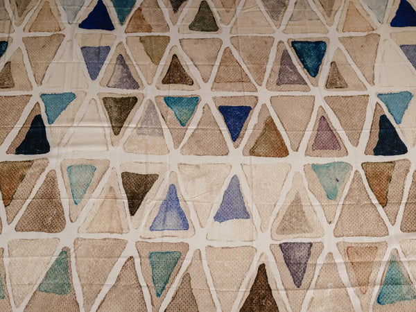 Close-up of Vellum luxury cotton bedsheet showcasing beige triangle mosaic print with blue and neutral watercolor accents