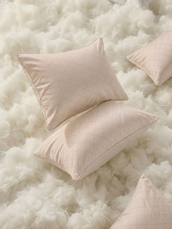 A close-up shot of two stacked beige pillows with a premium Jacquard self-pattern finish on matching organic cotton bedding