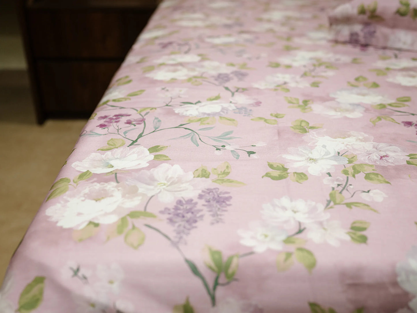 Close-up of blush pink floral organic cotton bedsheet showing premium fabric and botanical design 