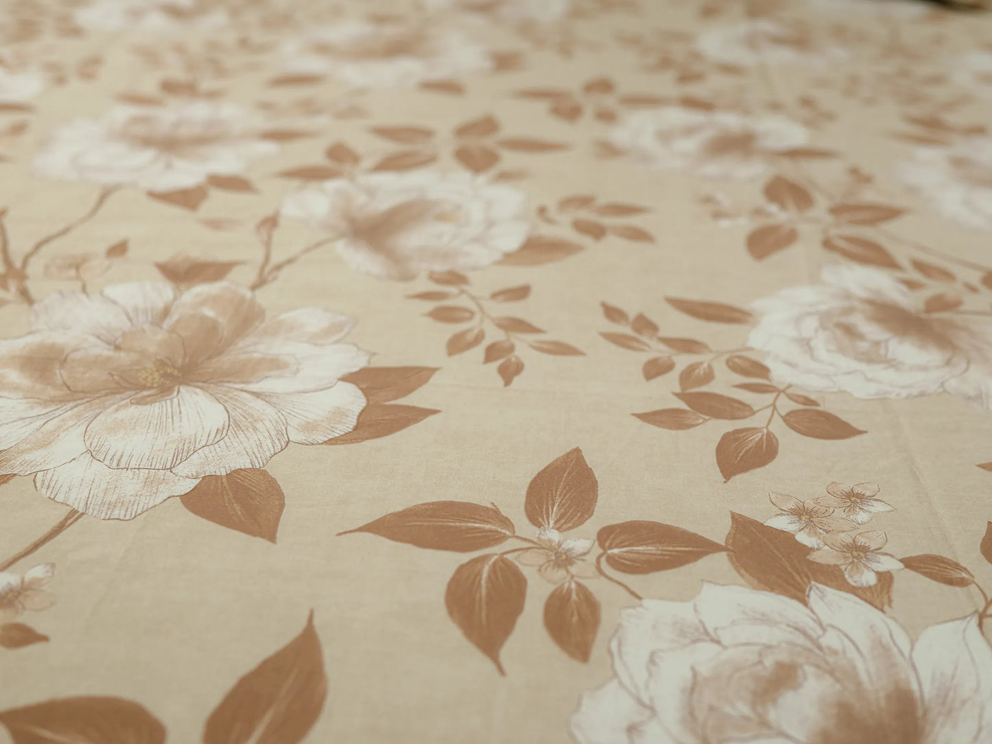 Macro view of elegant fawn and caramel floral botanical design on a premium 500 thread count organic cotton bedsheet