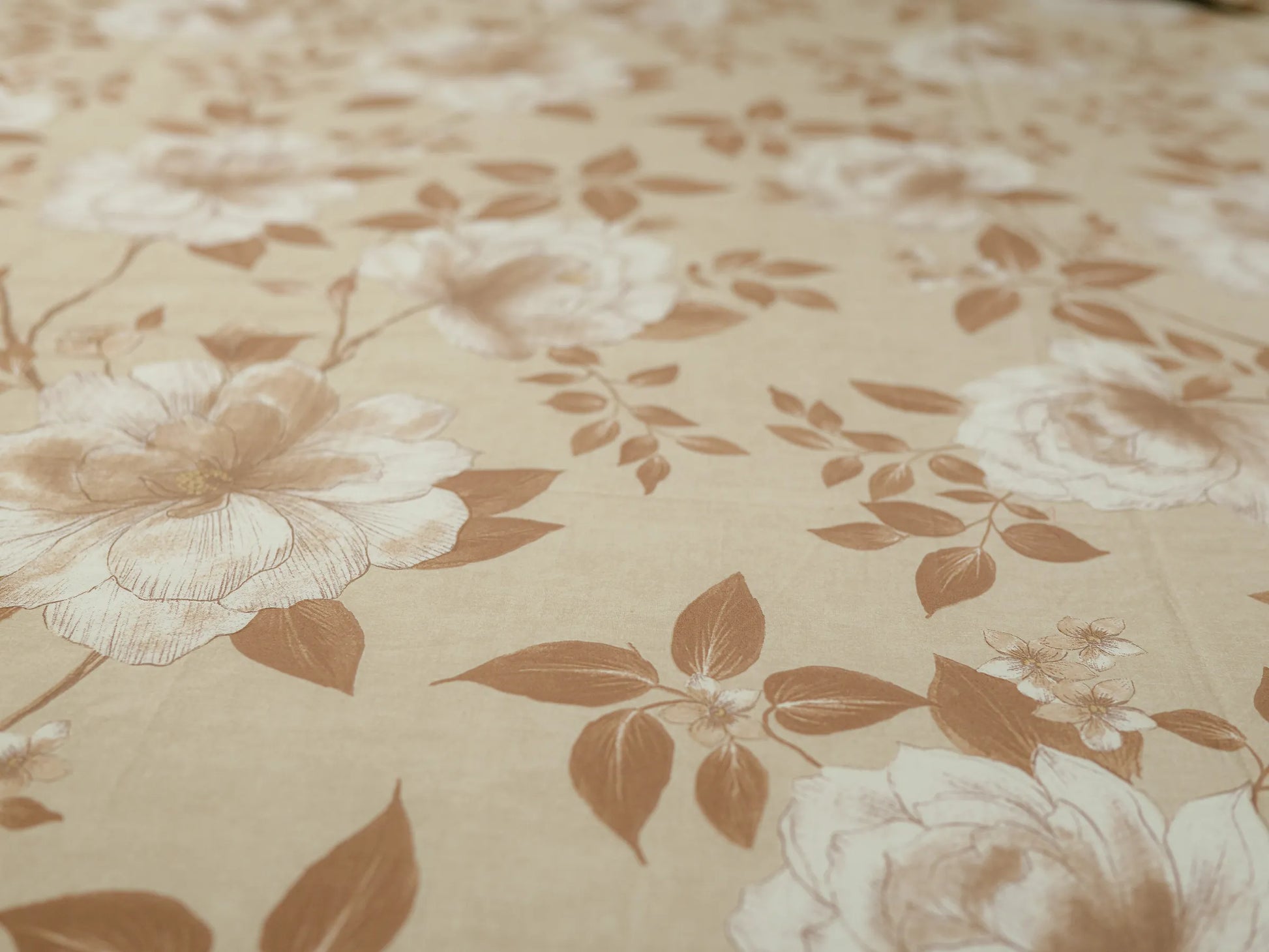 Macro view of elegant fawn and caramel floral botanical design on a premium 500 thread count organic cotton bedsheet