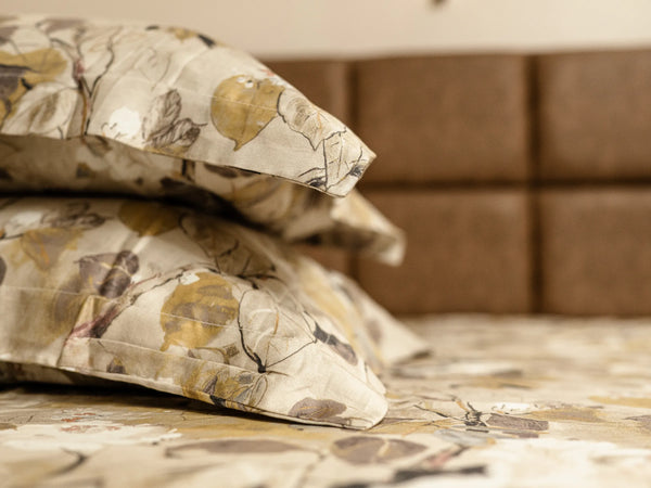 Two pillows kept one over another on a luxury ginger brown floral organic cotton with 500 thread count bedsheet on a super king bed