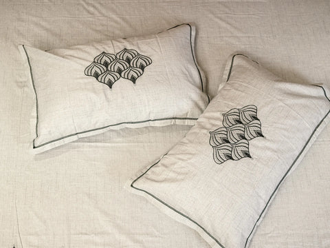 Solace greyish blue embroidered pillow covers on matching premium cotton bedsheet, showcasing delicate piping and artisanal craftsmanship