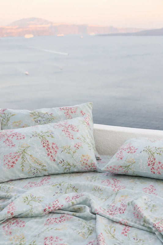 Close-up of pillow covers and bedsheet of Heirloom mint blue floral pillow covers in 100% organic cotton 500 thread count luxury bedding styled closer to ocean view