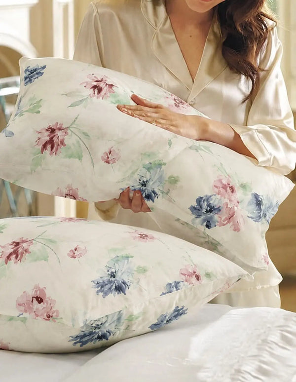 A lifestyle model is holding premium off white organic cotton floral pillow cover with elegant botanical print and soft 500 thread count fabric