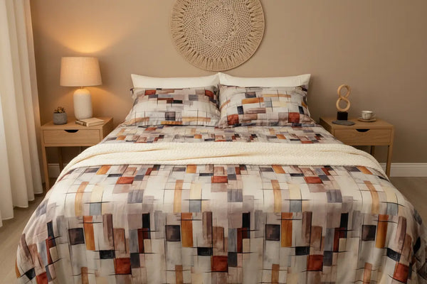 A full lifestyle bedroom look displaying Spectrum off white and mocha luxury bedsheet spread with matching pillows, displaying a modern abstract print