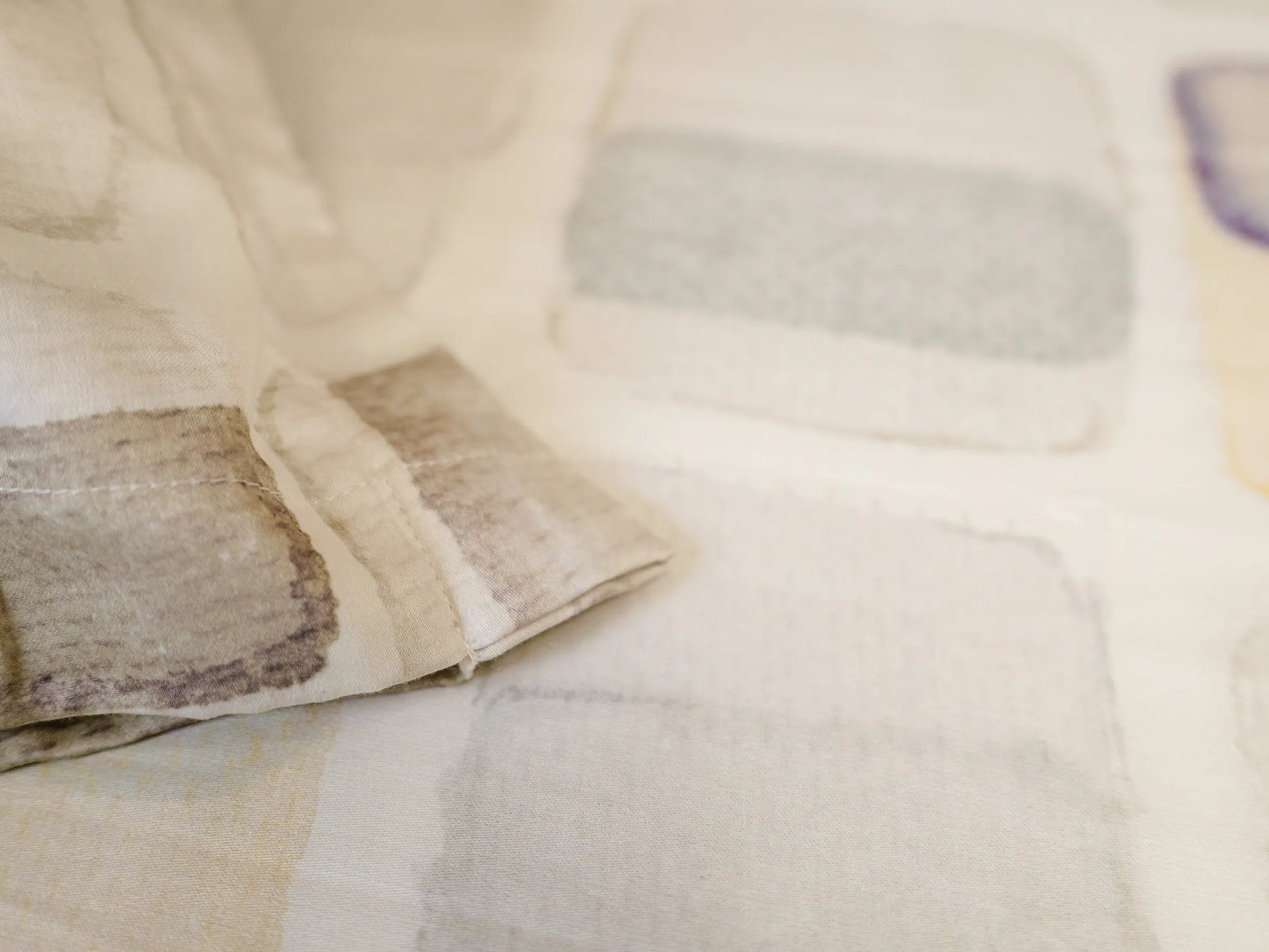 Detailed view of Motif luxury off white bedsheet featuring soft folds, modern geometric artwork, and premium 500 thread count organic cotton fabric