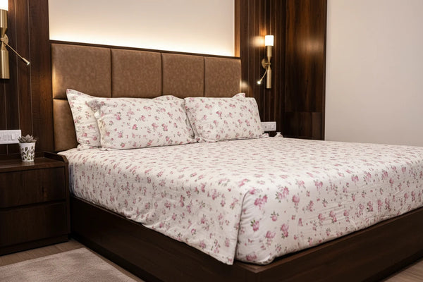 Display of full bed view of Manor luxury off white and rose pink floral organic cotton bedsheet with matching pillow covers styled on a premium bed in 500 thread count