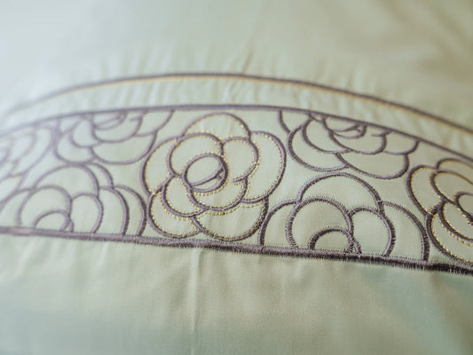 Close-up of embroidered pistachio green organic cotton pillow cover showcasing intricate floral embroidery and premium craftsmanship