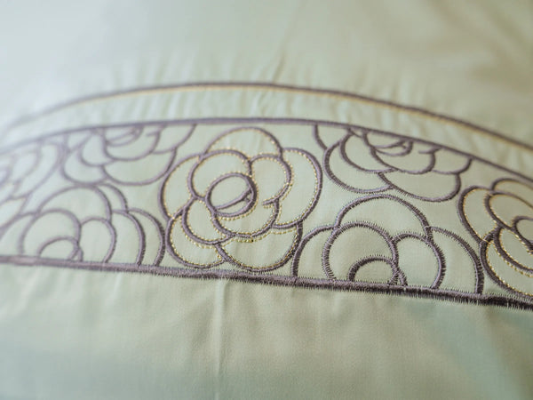 Close-up of embroidered pistachio green organic cotton pillow cover showcasing intricate floral embroidery and premium craftsmanship